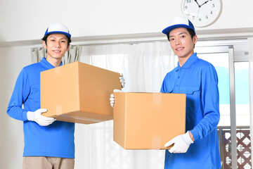 作業服を着た複数の男性が引っ越しの段ボールを持つイメージ