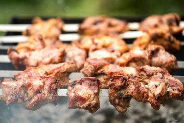 Shashlik or shish kebab preparing on barbecue grill over hot charcoal. Grilled pieces of pork meat on metal skewers.