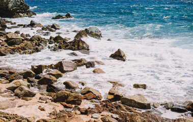 Fototapeta na wymiar Imagen de una orilla con rocas y arena en una playa mediterranea