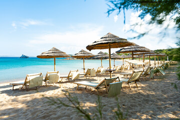 (Selective focus) Stunning view of some thatch umbrellas and sun chairs on a beach bathed by a beautiful, turquoise sea. Sardinia, Italy.