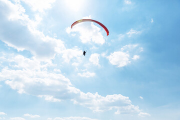 Yellow Paraglider tandem instructor with a tourist flying into the sky with clouds on a sunny day