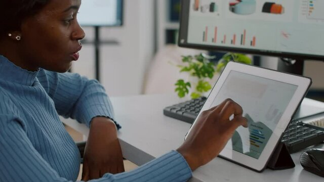 Black handicapped woman entrepreneur with locomotor disabilities immobilized in wheelchair using computer and tablet at same time working, business start-up office Busy multitasking african employee - Powered by Adobe