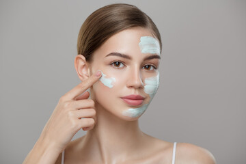Portrait of beautiful woman with blue cream mask on her face. Skin care concept. Gray background.