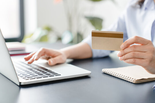 Cropped image of woman`s hands holding credit card and typing on laptop.Online shopping, e-commerce, internet banking, spending money, paying bills.