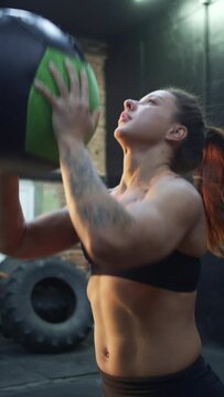 A strong athletic woman is training with a ball