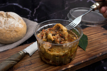 chicken and pickled aubergines in pots with very elegant knife and fork and homemade country bread on wooden board