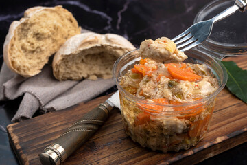 chicken and pickled aubergines in pots with very elegant knife and fork and homemade country bread on wooden board