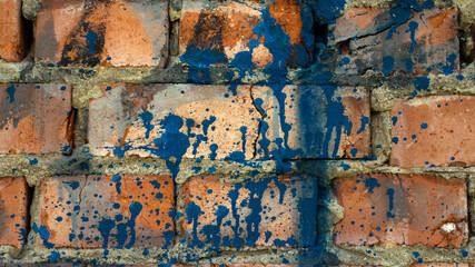 Background brick wall in a splash of paints. Copy space. The texture of the old red brick.