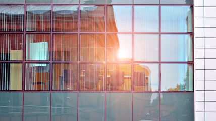 Fragment of the facade.  Facade texture of a glass mirrored office building. Light at sunrise with lens flare. 