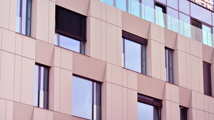 Abstract closeup of the glass-clad facade of a modern building covered in reflective plate glass. Architecture abstract background. Glass wall and facade detail.