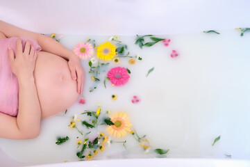 Flowers in bathroom water, belly of a pregnant woman and copy space