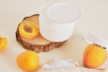 apricots plastic white jar for cream or cosmetics on a wooden podium from a saw cut wood on a light background