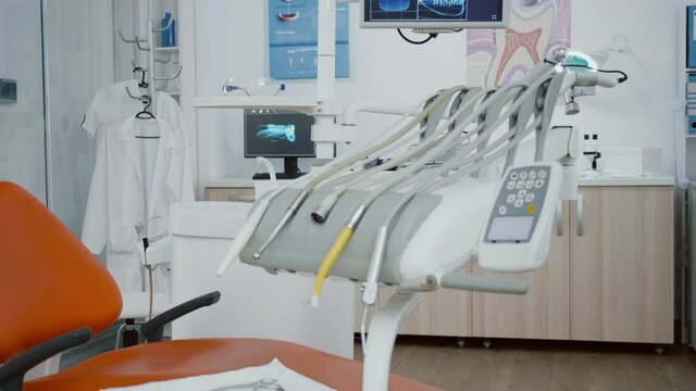 Close up revealing shot of medical orthodontic display with teeth xray images on it. Empty professional hospital stomatology chair with nobody in it equipped with dentistry tooth professional tools