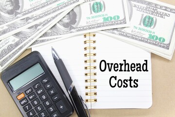 notebooks, pens, calculators, banknotes with the word overhead costs