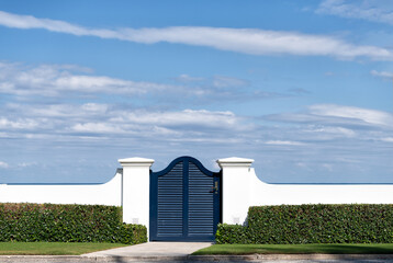 Blue wooden gate door in white fence and green hedge in Palm Beach Florida, USA, entrance