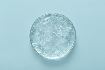 Transparent cosmetic gel in glass petri dish on blue background. Concept laboratory tests and research, making cosmetic.