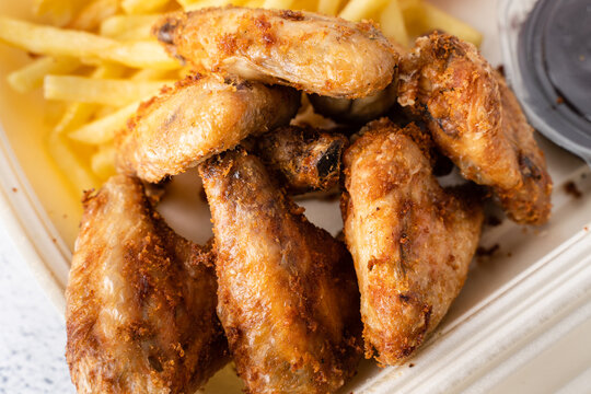 Fried chicken wings with french fries potato chips in portion for delivery pick up lunch close up