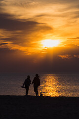 silhouette of two people under sunset beside ocean