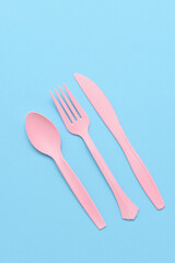 flat lay blue plastic utensils on a pink background