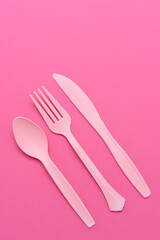 flat lay pink plastic utensils on a pink background