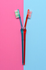 Two toothbrushes on a pink and blue background