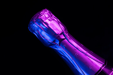 Bottle of sparkling champagne lit with neon light