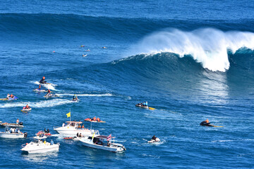 Spectators in boats watching a big wave surf contest at Jaws in Maui, Hawaii. 