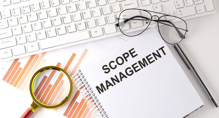 SCOPE MANAGEMENT text written on a notebook with keyboard, chart,and glasses