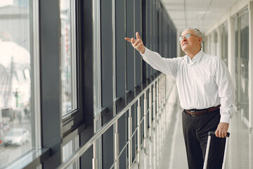 Fototapeta premium Elegant old man at the airport with a suitcase