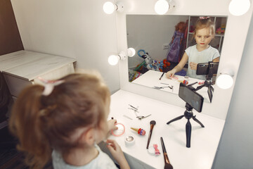 Cute little blogger with cosmetics recording video at home