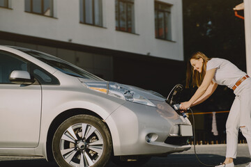 Woman charging electro car at the electric gas station