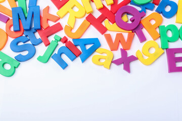 Many colorful magnetic letters on white background, top view
