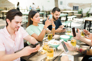 Young people using their phones at the bar