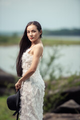 Wedding portrait of a cute bride asian woman white gorgeous wedding dress from the designer on the rock and the forest, Vintage style