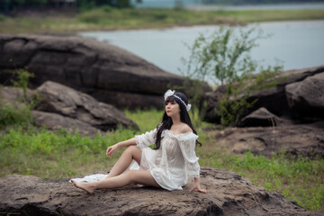 Wedding portrait of a cute bride asian woman white gorgeous wedding dress from the designer on the rock and the forest, Vintage style