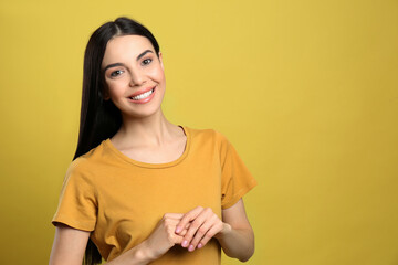 Obraz premium Portrait of happy young woman with beautiful black hair and charming smile on yellow background, space for text