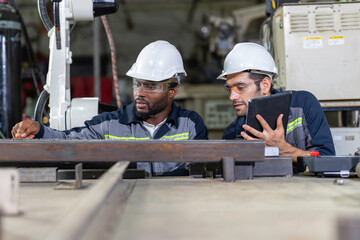 Two Industry engineers sitting and discussion work in the factory workshop.