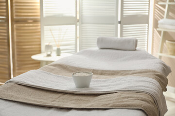 Massage table with soft towels and sea salt in spa salon