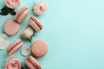 Flat lay composition with pink macarons and roses on light blue background. Space for text
