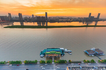 the Ganjiang River is full of water, with ships passing by, tall buildings on both sides, and the city skyline is dazzled by the setting sun.