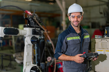 Portrait shot of mechanical engineer holding the robotic arms controller and in factory work shop..