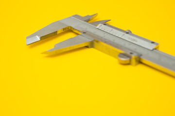 Selective focus of iron Vernier Calipers on yellow background  and copy space