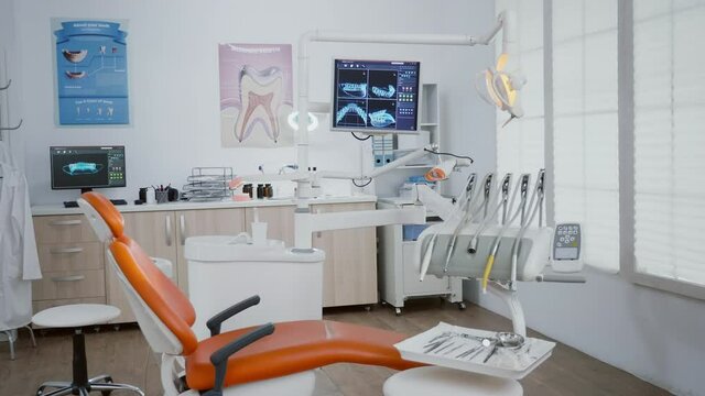 Revealing shot of stomatology chair with nobody in it, teeth diagnosis xray images on display. Medical clinic orthodontic empty room, ready for healdcare treatment, modern dentist office for oral care