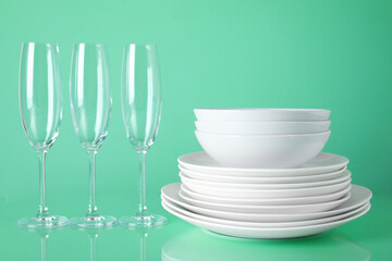 Set of clean tableware on light green background
