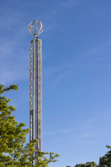 Fototapeta premium Tall light covered carnival spire emerges from behind tall trees