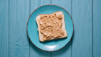 Piece of toasted bread with a peanut butter. Blue background. Top view.
