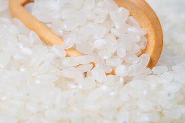 Raw rice japanese with wooden scoop on background.