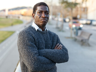 Portrait of cheerful African-American man in warm sweater in urban environment