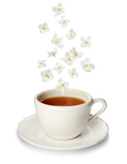 Beautiful jasmine flowers falling into cup of hot freshly brewed tea on white background