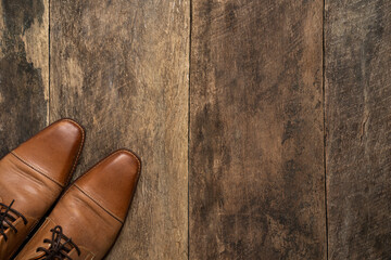 Male brown leather shoes on old wooden background.